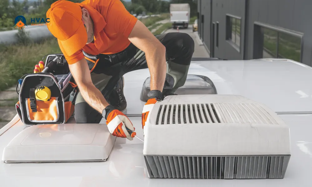 A technician in orange uniform and cap repairs an HVAC unit on a white rooftop, with tools nearby. The setting is industrial and focused on precision.